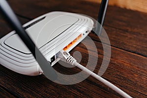 Connected LAN cable to a router on a dark wooden table. High-speed wi-fi internet. Stable internet connection.