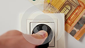 Connecting an electrical consumer plug to a home socket with an inserted euro bill.