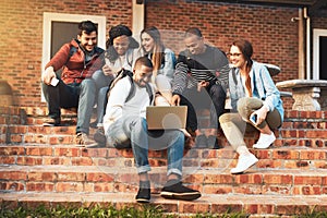 Connecting with like minded young go getters. Shot of a group of students using a laptop together on campus.