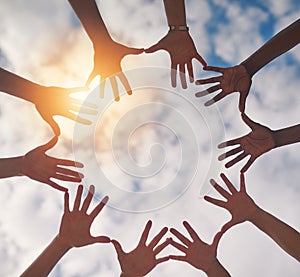 Connecting with nature and each other. Low angle shot of a group of unidentifiable people making a circle with their