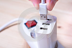 Connecting A White USB Cable To A White USB Charger Which Is Plugged Into A Power Strip
