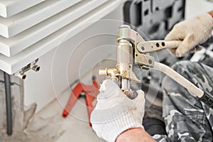 Connection heating pipes to white Radiator in a new apartment under construction. Work As A Plumber, mounting water