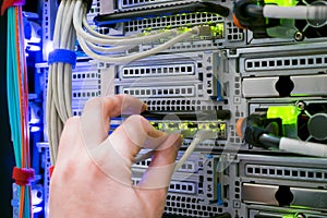 Connection of trunk cables to the network interface of the modern server. Service work in the datacenter server room. The hand of