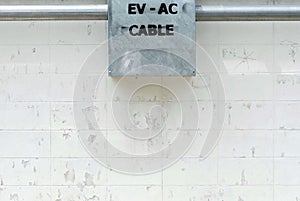 A connector box of a cable EV car charger on the cement wall of the frence
