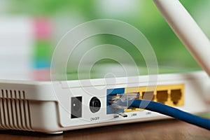 The connectors of the white router and the blue cable in the bright office