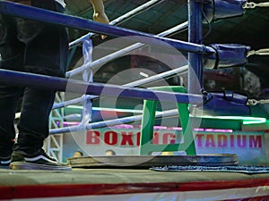 A connerman standing inside a boxing ring  trainer / coach  waiting to assist and administer to the fighter during a bout /