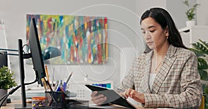 A conscientious organized office worker in a large corporation sits at desk synchronizing documents on tablet with