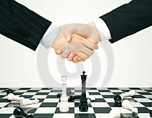 Consensus concept with men shaking hands and chess pawns