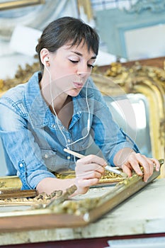 conservator cleaning golden frame