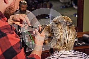 Consider yourself warned. Hipster client getting haircut. Barber scissors. Guy with long dyed blond hair close up rear