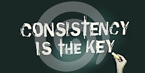 Consistency is the Key chalkboard with text and hand holding piece of cahlk. Business success concept