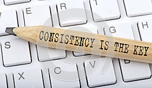 CONSISTENCY IS THE KEY text on pencil on the keyboard background