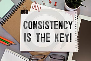 CONSISTENCY IS THE KEY, text on white paper on gray background