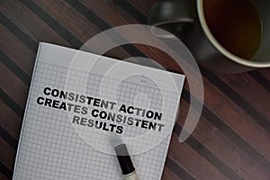 Consistent Action Creates Consistent Results write on a book isolated on Wooden Table photo