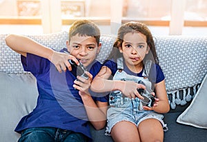 Console, portrait of children playing video games and on sofa in living room. Bonding time or happiness, technology and