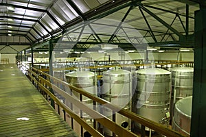 Barrels and technical equipment inside the wine cellar of a winery, Cape Town, South Africa.