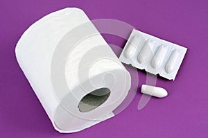 Constipation concept with toilet paper roll and suppositories on pink background