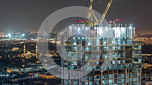 Construction activity in Dubai downtown with cranes and workers night timelapse, UAE.