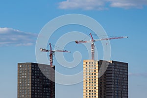 Construction of apartment buildings. Two tower cranes on the background of two houses under construction