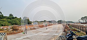 Construction of an asphalt road being cleaned by workers at a housing project site.