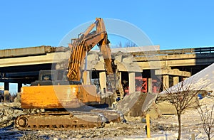 Construction of the automobile bridge. Excavator hydraulic crushes concrete slabs.