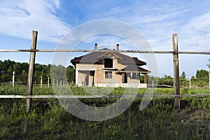 Construction of brick family house in suburbs. Shell of town home with completed walls and roof. Building a home in the field