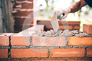 Construction bricklayer worker building walls with bricks, mortar and putty knife photo