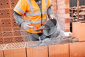 Construction bricklayer worker building walls with bricks, mortar and putty knife
