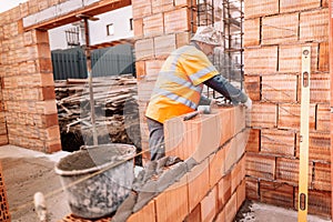 Construction bricklayer worker building walls with bricks, mortar and putty knife