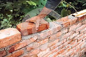 Industrial Construction bricklayer worker building walls with bricks, mortar and trowel