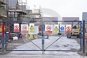 Construction building site entrance gate fence and health and safety signs