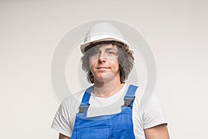 Construction, building and workers concept - Closeup portrait of handsome curly white man in builders helmet.
