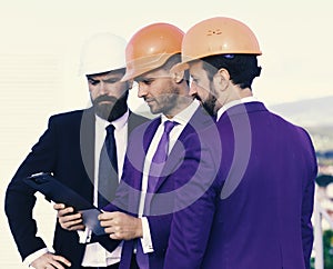Construction and business concept. Men with beard and concentrated faces discuss plan. Board of architects wear smart