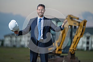 Construction business owner. Man in suit and hardhat halmet at building construction site. Civil engineer worker in