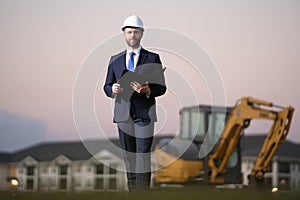Construction business owner. Man in suit and hardhat halmet at building construction site. Civil engineer worker in