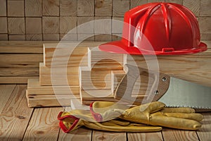 Construction carpentry tools red helmet glaves and handsaw on wooden background