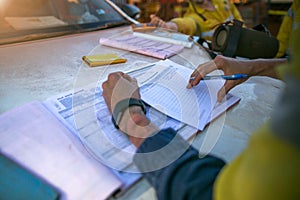 Construction coal miner supervisor conducting safety checking on job hazards analysis on hot work permit before sign off