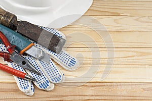 Construction concept. Construction tools, work gloves and white helmet on wooden background . Copy space for text.