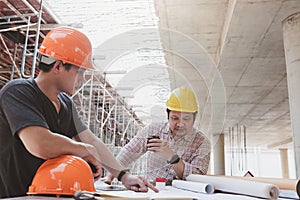 Construction concept of Engineer and Architect working with construction model and blueprint at construction site, Engineer and