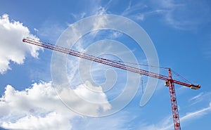 Construction concept. Red tower crane under cloudy sky background. Under view, space