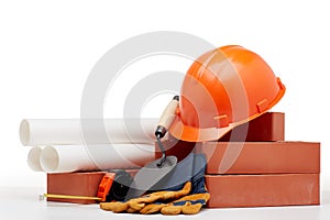 Architectural blueprints, stack of bricks, masonry trowel,  construction hard hat on white background. Construction concept