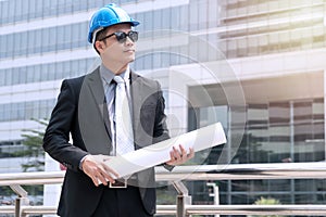 Construction concept. Success Engineer blue helmet for safety and checking building plans. Young businessman wear sunglasses