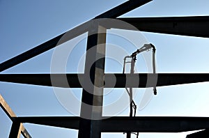 Construction of concrete structure of industrial hall of warehouse. the concrete feeder arm from the mixer bends over the beams an