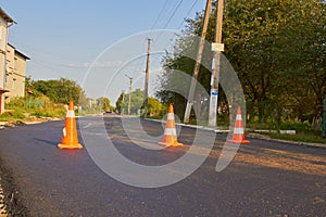 construction cones on a new asphalt road,construction of asphalt on the street, the road is closed with orange cones
