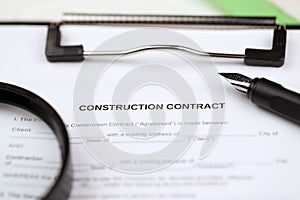 Construction contract form on A4 tablet lies on office table with pen and magnifying glass