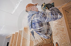 Construction Contractor Attaching Drywall Elements to the House Ceiling