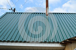 Construction of a country house with a metal roof covered with green siding