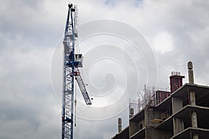 Construction crane above the building under construction against the sky with clouds