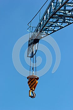 Construction crane arm with hook against blue sky background