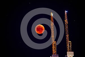 Construction crane on the background of a full red moon. Red moon, total lunar eclipse.